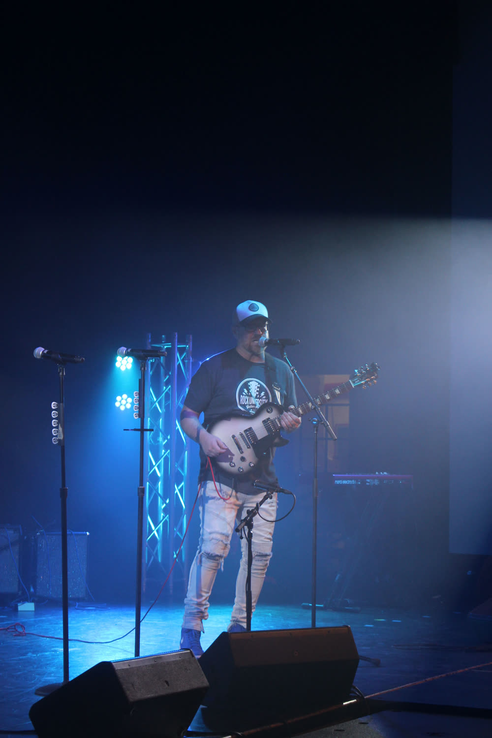 Rock U student performing on stage with professional lighting at Rock U Live