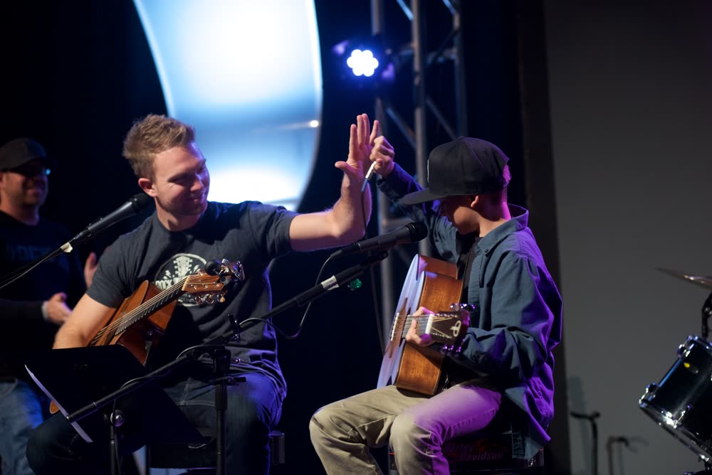 Instructor high-fiving student on stage at Rock U Live