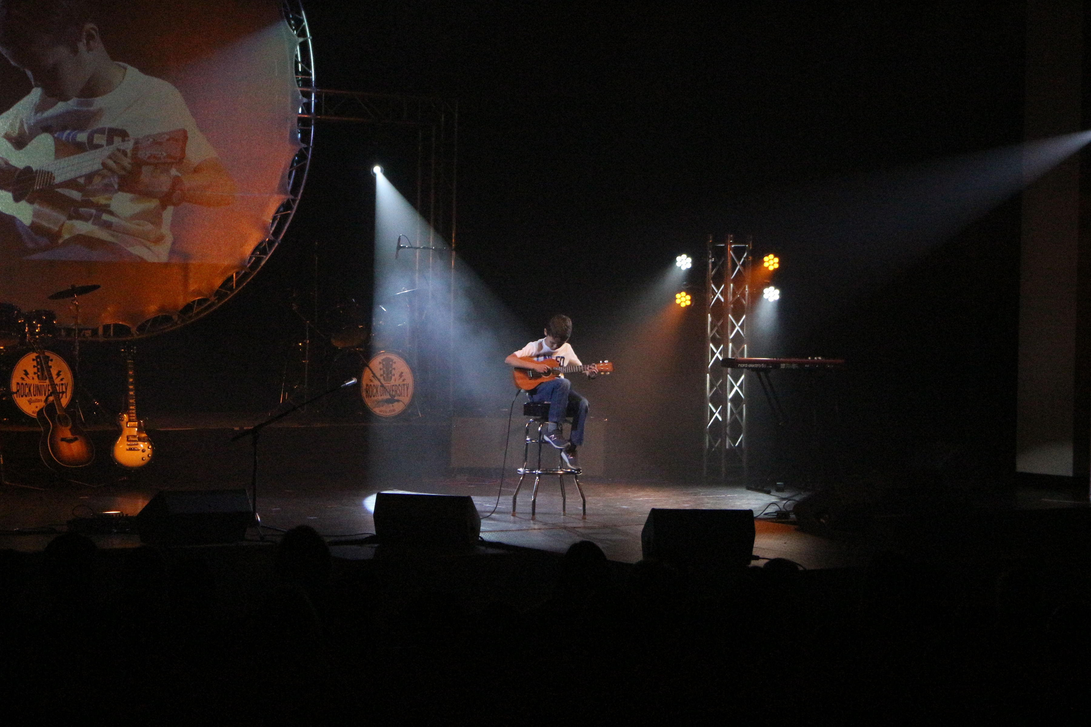 Rock U student performing solo on stage with professional lighting at Rock U Live